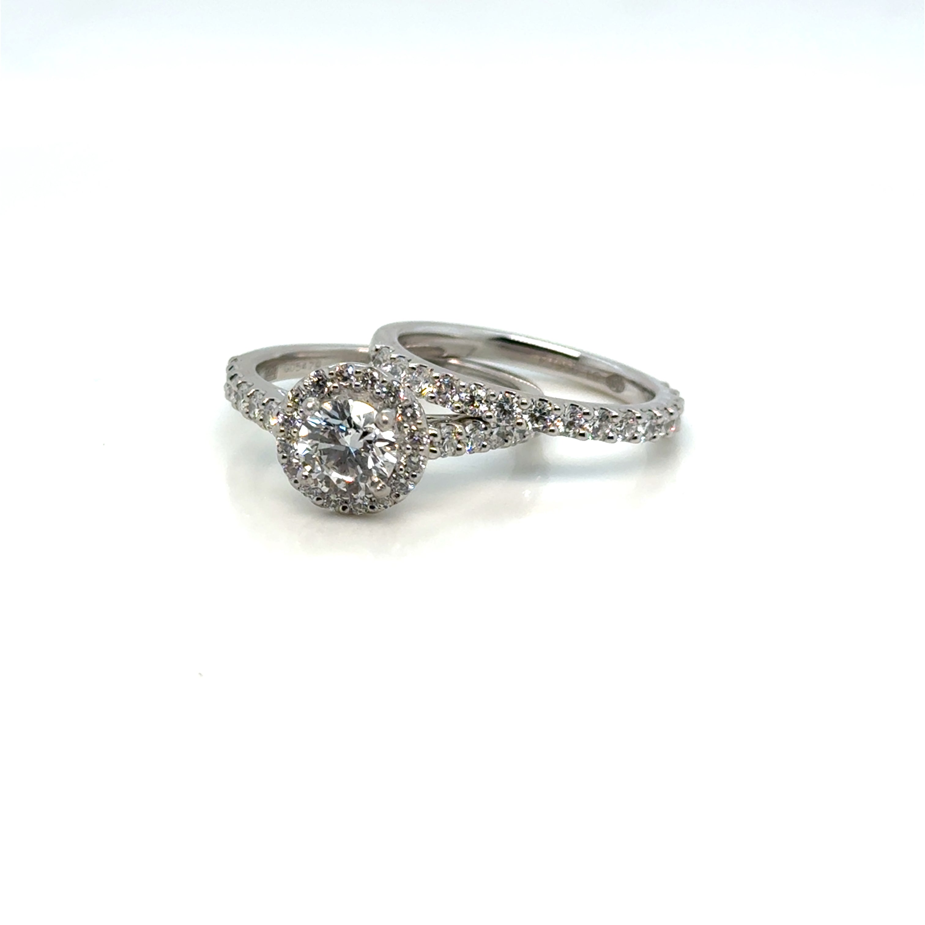 Platinum diamond halo wedding set on white background – elegant bridal jewelry featuring a halo-style engagement ring and a matching diamond wedding band crafted in polished platinum.